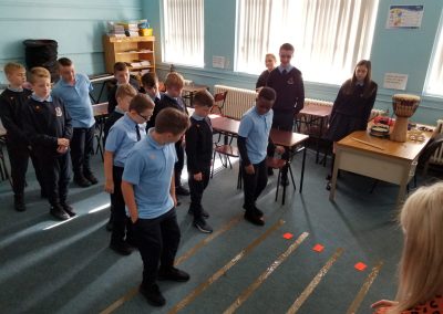 Students standing on taped lines on the ground that act as a musical stave